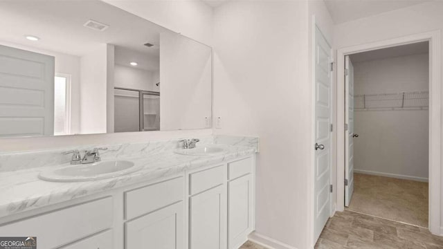 bathroom featuring a shower with door and vanity