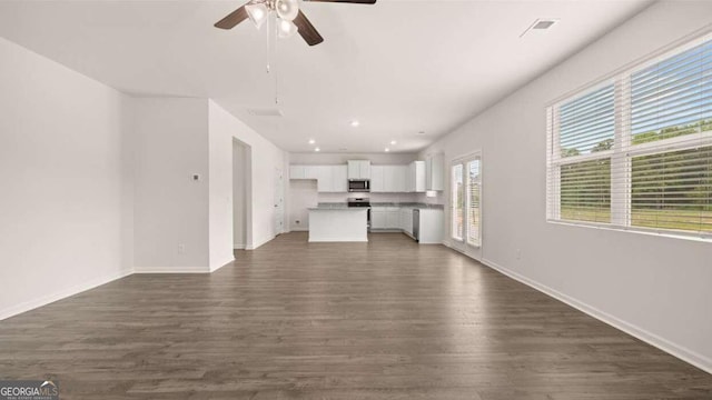 unfurnished living room with ceiling fan and dark wood-type flooring