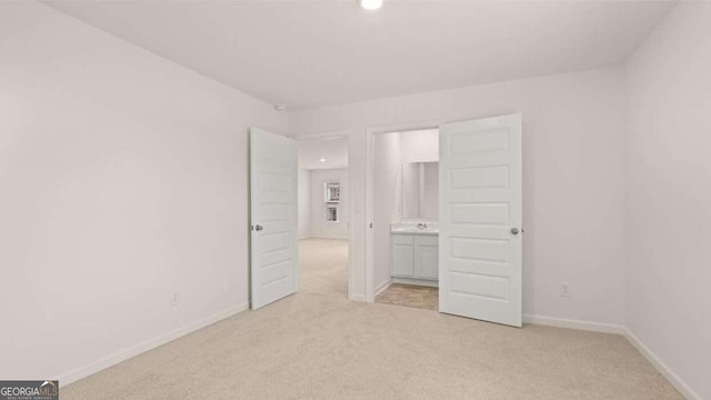 unfurnished bedroom featuring light carpet, sink, and ensuite bathroom