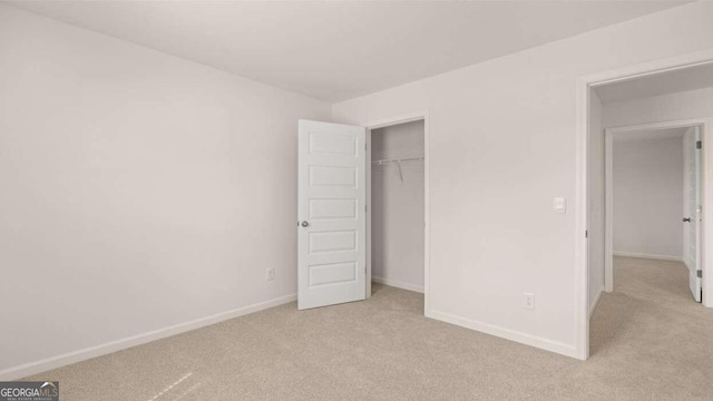 unfurnished bedroom with light colored carpet and a closet