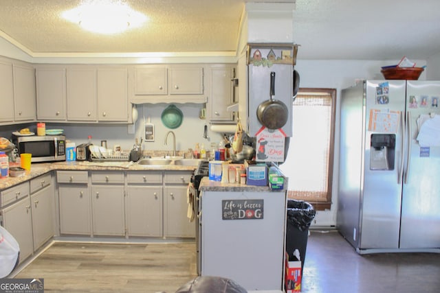 kitchen featuring sink, light hardwood / wood-style flooring, stainless steel appliances, and a textured ceiling