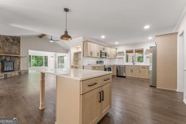 kitchen featuring dark hardwood / wood-style flooring, hanging light fixtures, ceiling fan, a stone fireplace, and appliances with stainless steel finishes