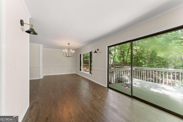 unfurnished room with ornamental molding, dark wood-type flooring, and an inviting chandelier