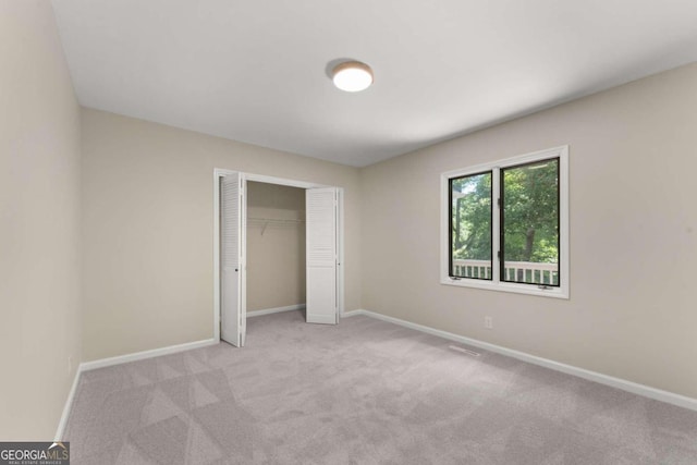 unfurnished bedroom with light carpet and a closet