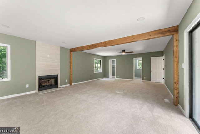 unfurnished living room with a healthy amount of sunlight, a fireplace, and carpet flooring