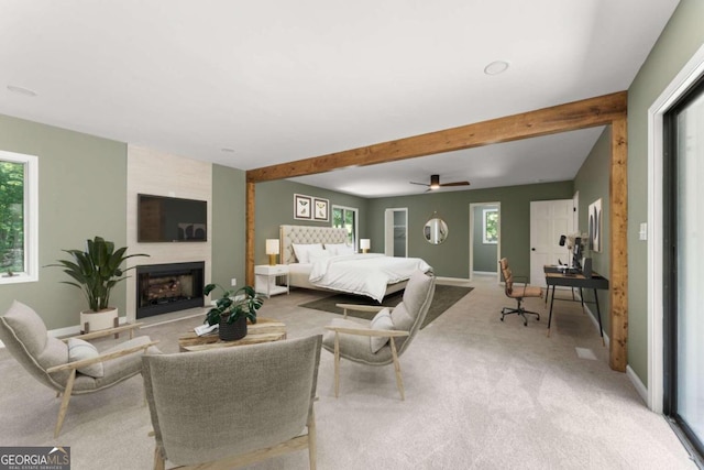 living room featuring a healthy amount of sunlight, beamed ceiling, a large fireplace, and carpet flooring