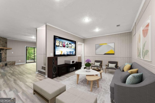 living room with crown molding, a textured ceiling, a fireplace, and wood-type flooring