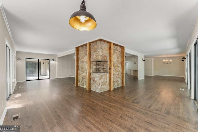 unfurnished living room featuring a chandelier, ornamental molding, and dark hardwood / wood-style flooring