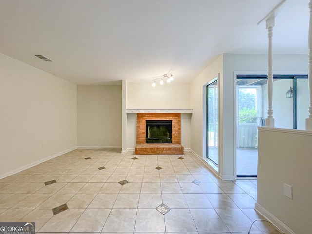 unfurnished living room featuring light tile patterned floors and a brick fireplace