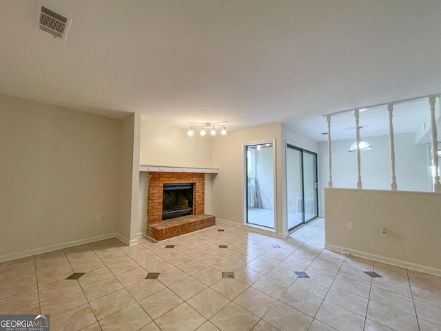 unfurnished living room featuring a fireplace, light tile patterned floors, and rail lighting