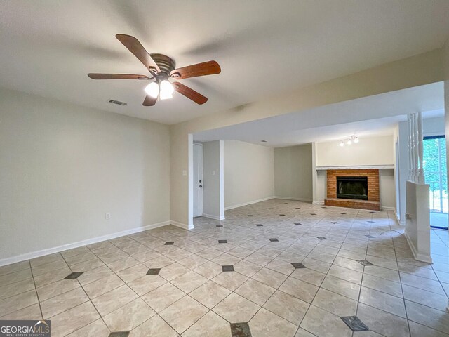 unfurnished living room with ceiling fan, a fireplace, and light tile patterned floors