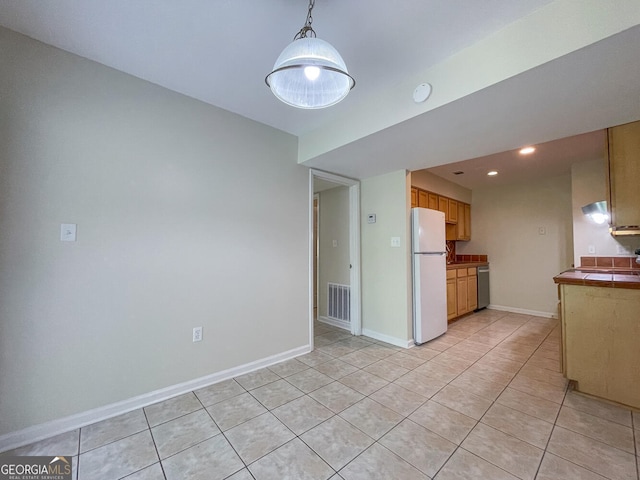 kitchen featuring hanging light fixtures, dishwasher, white fridge, tile counters, and light tile patterned flooring