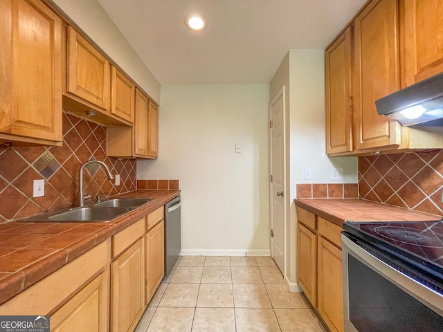 kitchen with sink, stainless steel appliances, tasteful backsplash, tile countertops, and light tile patterned floors