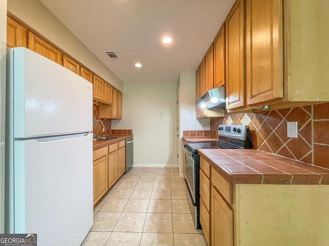 kitchen with decorative backsplash, appliances with stainless steel finishes, tile countertops, and sink