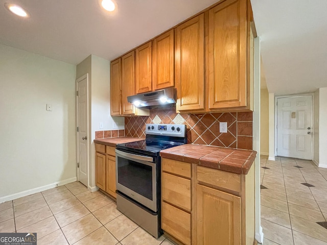 kitchen featuring stainless steel range with electric stovetop, tile counters, light tile patterned floors, and tasteful backsplash