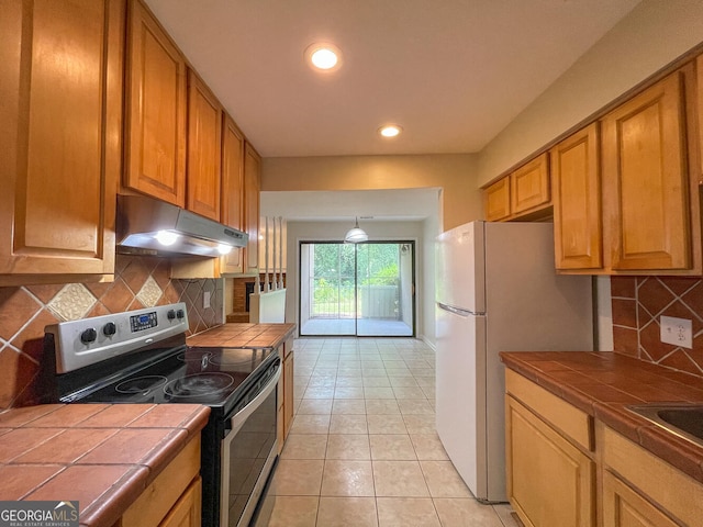 kitchen featuring light tile patterned floors, backsplash, tile countertops, and stainless steel electric range