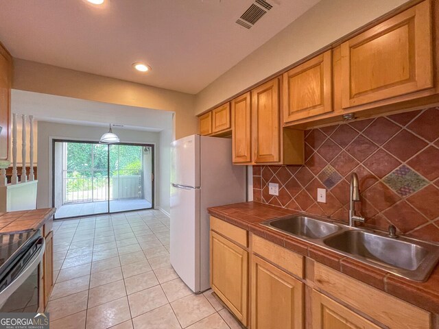 kitchen with tile counters, sink, hanging light fixtures, tasteful backsplash, and light tile patterned flooring