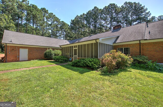 back of house with a yard and a sunroom