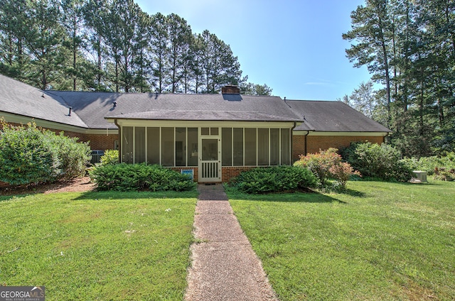 back of house with a lawn and a sunroom