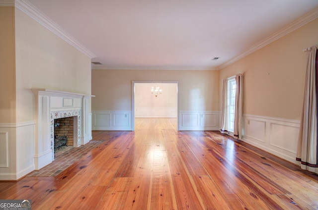 unfurnished living room with light hardwood / wood-style floors, crown molding, and a notable chandelier