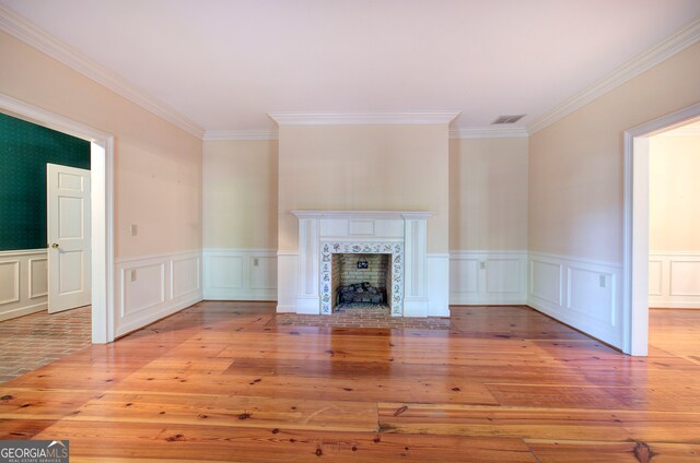 unfurnished living room featuring crown molding, a tile fireplace, and light hardwood / wood-style floors