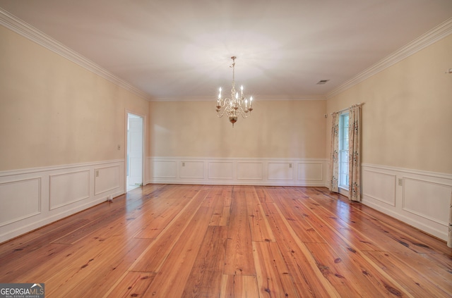 spare room featuring a notable chandelier, ornamental molding, and light hardwood / wood-style flooring