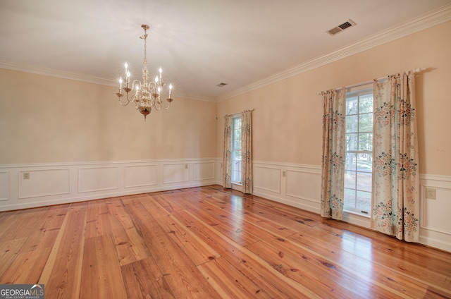 spare room featuring ornamental molding, light hardwood / wood-style flooring, and a notable chandelier