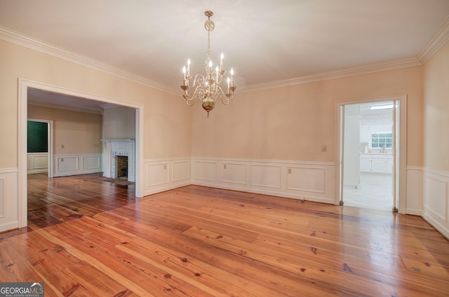 spare room featuring a notable chandelier, ornamental molding, and wood-type flooring