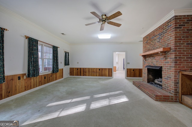 unfurnished living room featuring ornamental molding, wooden walls, a brick fireplace, and light colored carpet