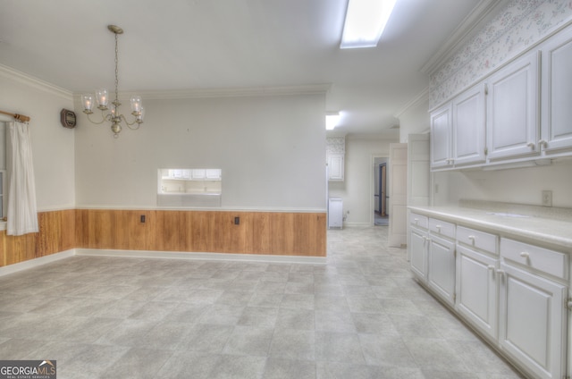 empty room with crown molding, wooden walls, and a notable chandelier