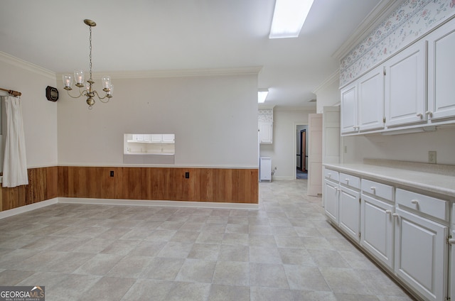 interior space featuring ornamental molding, an inviting chandelier, and white cabinetry