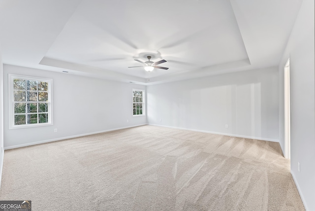 carpeted empty room featuring a tray ceiling and ceiling fan