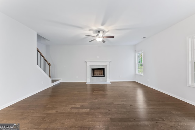 unfurnished living room featuring a high end fireplace, dark hardwood / wood-style flooring, and ceiling fan