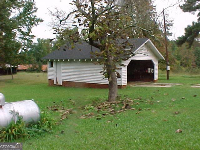 view of home's exterior featuring a garage, a yard, and an outbuilding