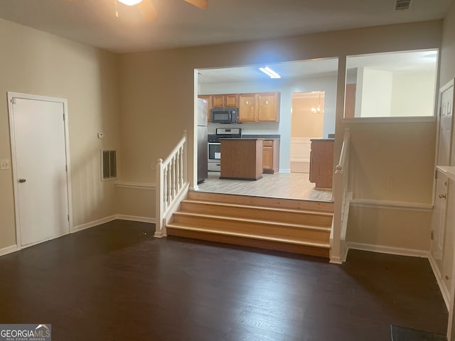 staircase with hardwood / wood-style floors and ceiling fan with notable chandelier