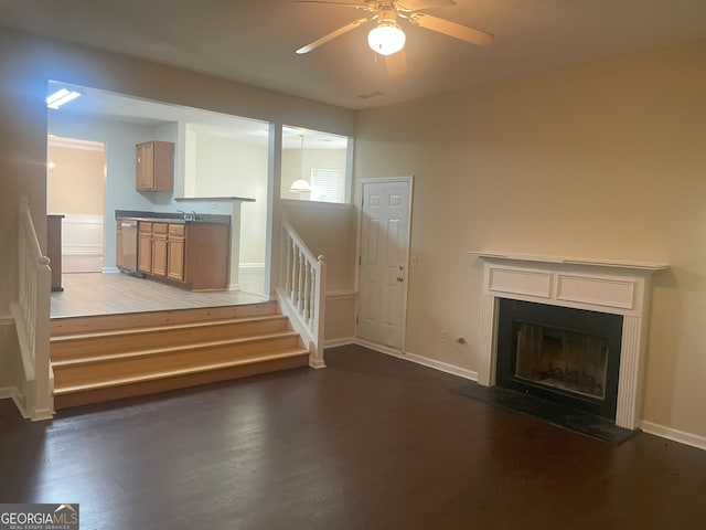 unfurnished living room featuring ceiling fan and dark wood-type flooring