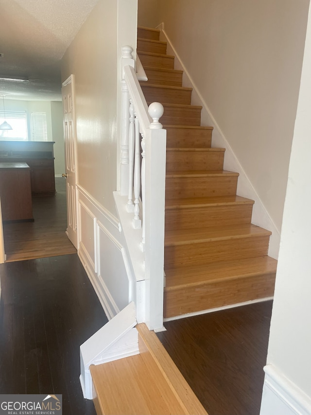 staircase with hardwood / wood-style floors and a textured ceiling