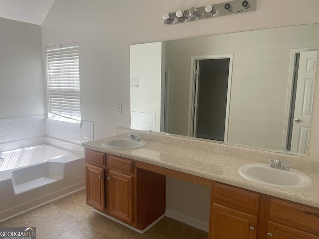 bathroom featuring a bath, a textured ceiling, and vanity