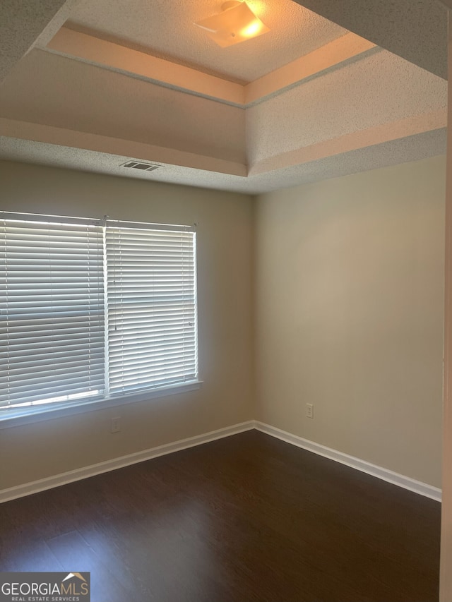 unfurnished room with dark hardwood / wood-style floors and a raised ceiling