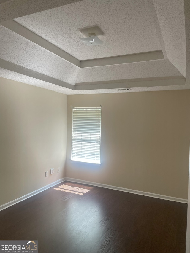 unfurnished room with hardwood / wood-style floors, a textured ceiling, and a tray ceiling