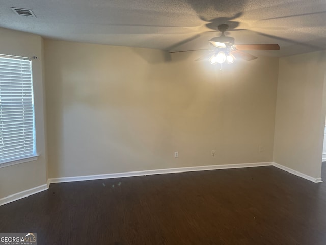 empty room featuring ceiling fan, dark hardwood / wood-style flooring, and a textured ceiling