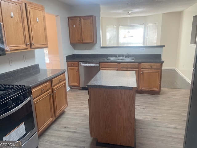 kitchen with sink, a kitchen island, light hardwood / wood-style flooring, and appliances with stainless steel finishes