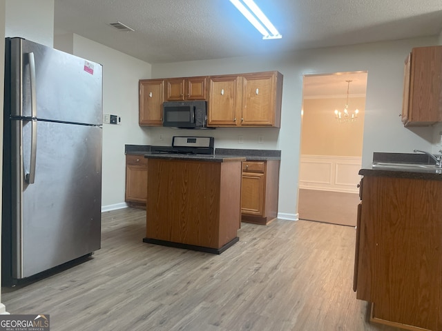 kitchen with stainless steel fridge, sink, an inviting chandelier, range, and light hardwood / wood-style floors