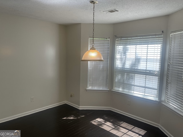 unfurnished room with dark hardwood / wood-style floors, a healthy amount of sunlight, and a textured ceiling