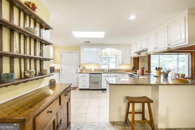 101 Huntington Dr, Dublin, GA 31021 - kitchen with stainless steel dishwasher, a peninsula, white cabinets, dark stone countertops, and a skylight
