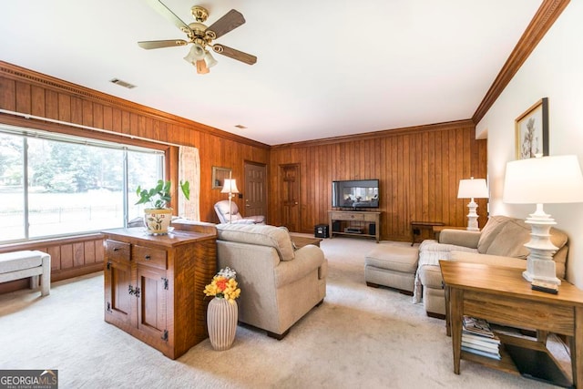 carpeted living room featuring crown molding, ceiling fan, and wood walls