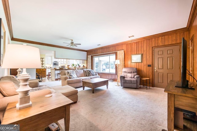 living room featuring ceiling fan, light carpet, crown molding, and wooden walls