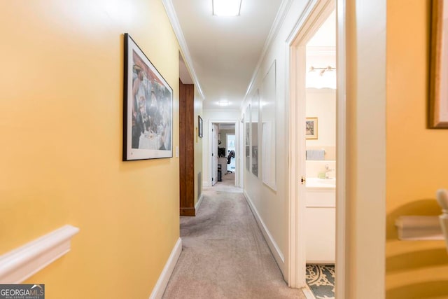 hallway with light colored carpet and ornamental molding