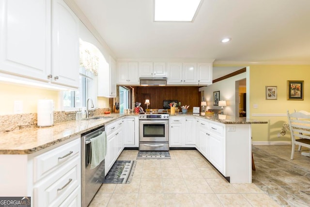 kitchen featuring light stone countertops, stainless steel appliances, white cabinets, kitchen peninsula, and ornamental molding