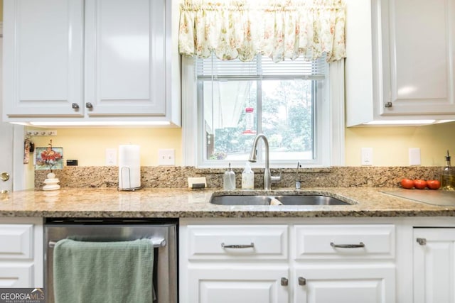 kitchen featuring light stone countertops, white cabinetry, sink, and stainless steel dishwasher